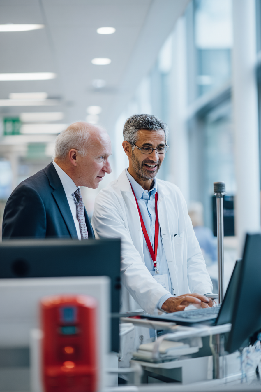 A compliance officer and colleague reviewing secure patient records at a workstation