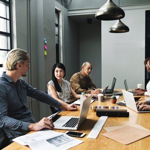 People sitting at conference table with laptops